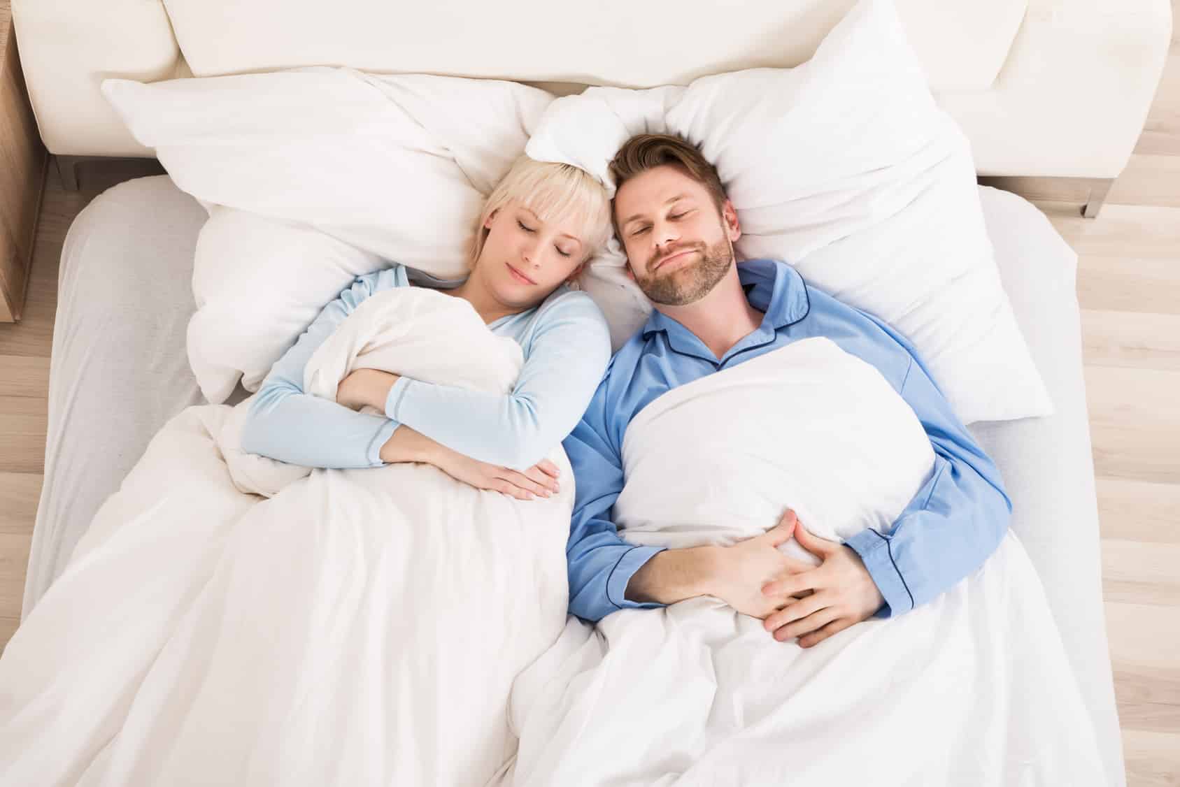 High Angle View Of Young Couple Sleeping On Bed At Home