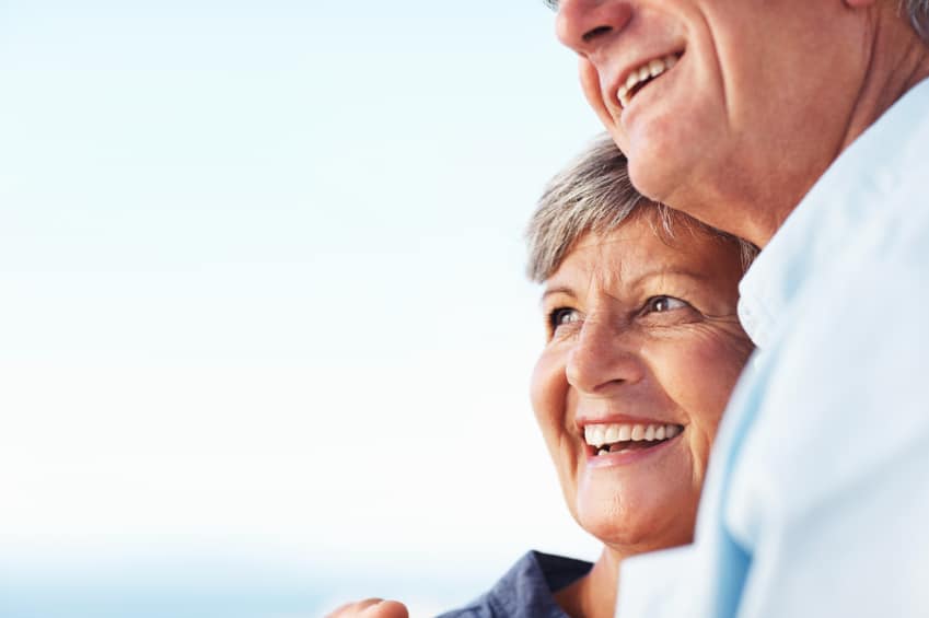 Closeup of happy mature woman and man smiling against sky